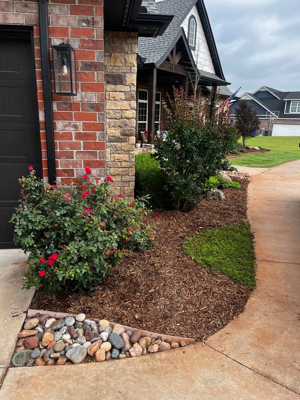 landscaped driveway featuring vibrant flowers, mulch beds, and decorative stones
