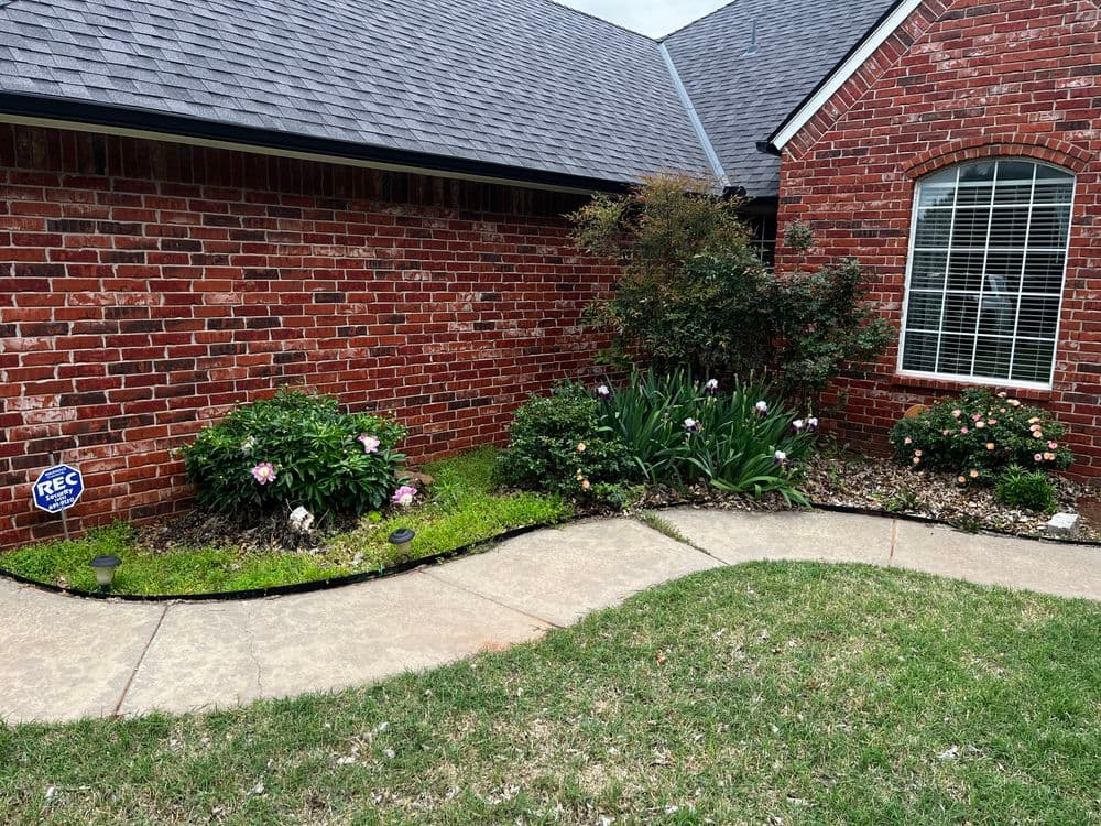 Brick house exterior with landscaped garden, flowers, and curved walkway.